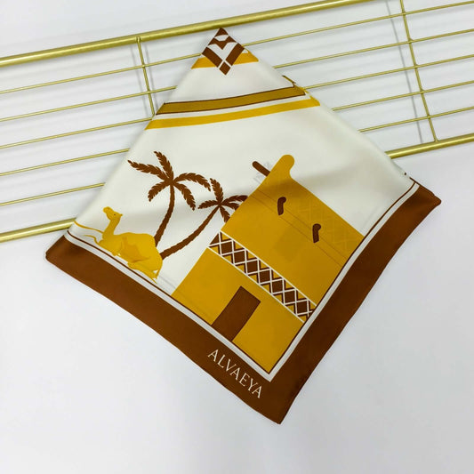 Najd Heritage Silk Scarf design featuring traditional architecture, camels, and palm trees in warm tones, from Alvaeya.