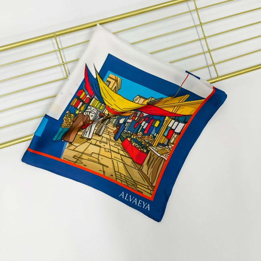 Ibn Batuta Silk Scarf design featuring vibrant market scenes and architectural elements from the Lineage Collection by Alvaeya.
